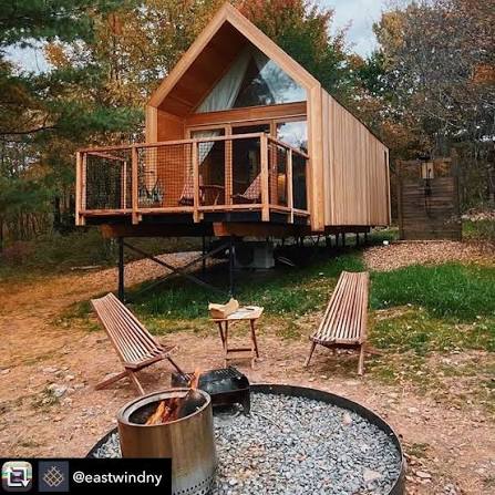 A-frame timber cabin on stilts with fire pit seating area